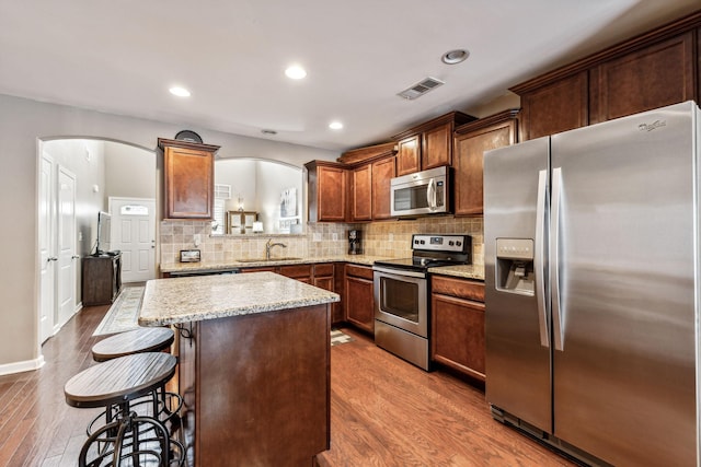 kitchen featuring a breakfast bar, sink, tasteful backsplash, appliances with stainless steel finishes, and a kitchen island