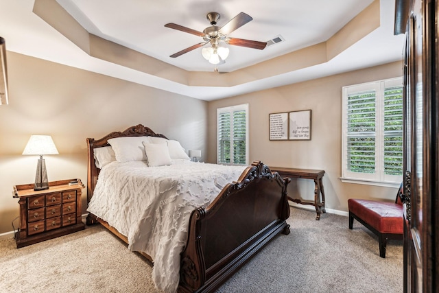 carpeted bedroom featuring a raised ceiling and ceiling fan