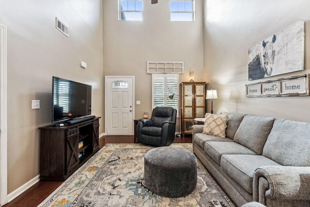 living room with dark wood-type flooring and a high ceiling