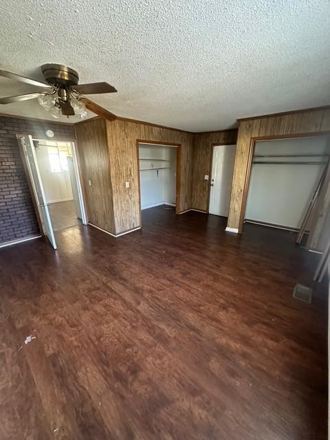 unfurnished living room with dark wood-type flooring, ceiling fan, and a textured ceiling