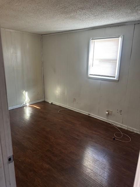 unfurnished room featuring dark wood-type flooring and a textured ceiling