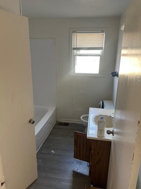 bathroom with vanity, toilet, a bathing tub, and hardwood / wood-style floors