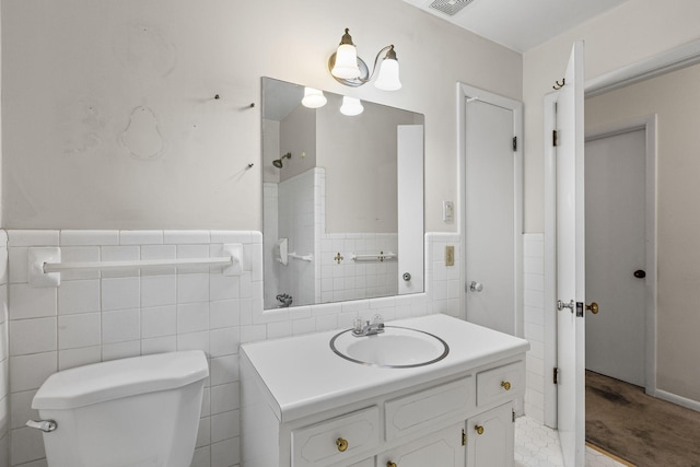 bathroom featuring vanity, tile walls, and toilet