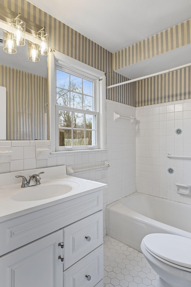 full bathroom with tile walls, tile patterned flooring, vanity, tiled shower / bath combo, and toilet