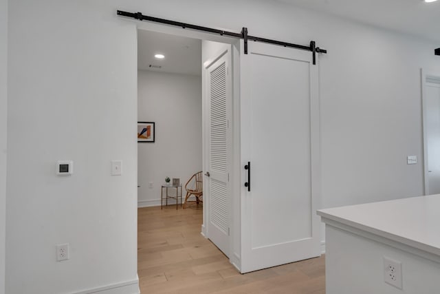 corridor featuring a barn door and light hardwood / wood-style flooring