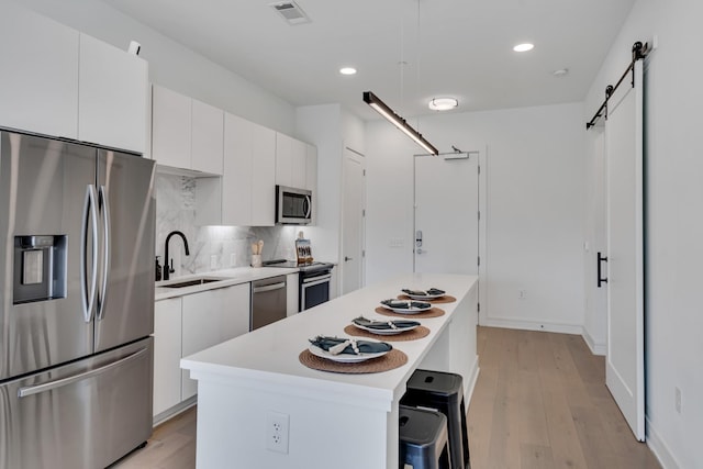 kitchen with white cabinetry, stainless steel appliances, a center island, and sink