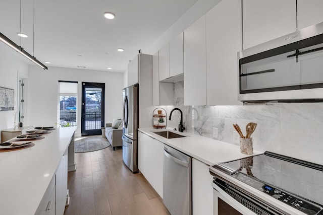 kitchen featuring sink, light hardwood / wood-style flooring, appliances with stainless steel finishes, tasteful backsplash, and white cabinets