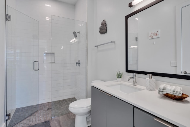 bathroom featuring vanity, a shower with shower door, and toilet