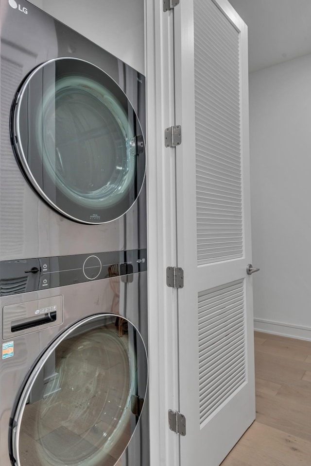 laundry area featuring stacked washer / drying machine and light hardwood / wood-style flooring