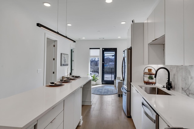 kitchen with sink, stainless steel appliances, light hardwood / wood-style floors, decorative backsplash, and white cabinets