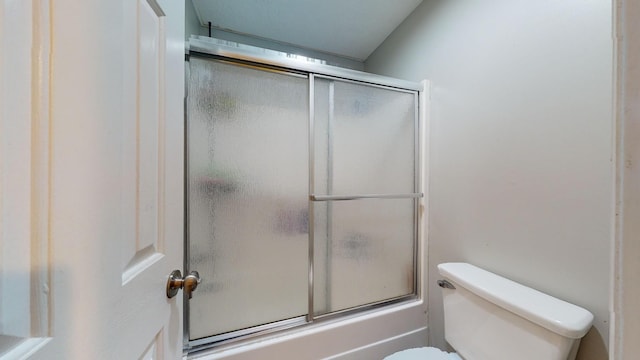 bathroom with bath / shower combo with glass door and toilet