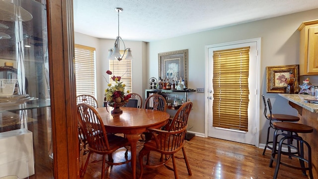 dining area featuring hardwood / wood-style flooring, indoor bar, and a textured ceiling