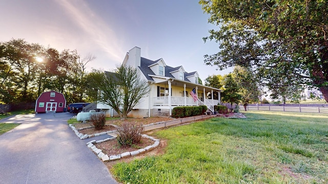 view of front of house featuring an outbuilding, a porch, and a front yard