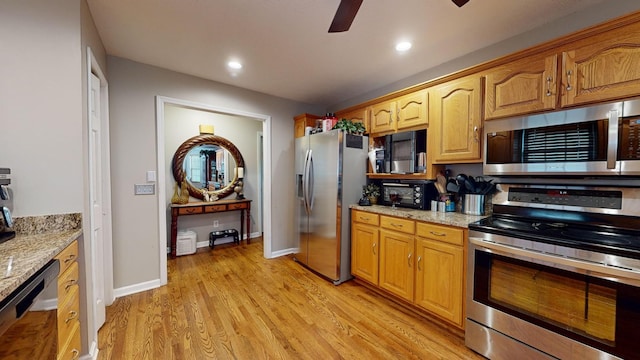 kitchen featuring light stone counters, black appliances, ceiling fan, and light wood-type flooring