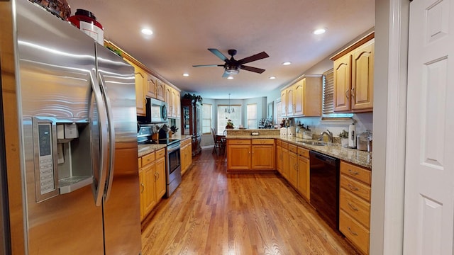 kitchen with sink, light stone counters, light wood-type flooring, kitchen peninsula, and stainless steel appliances