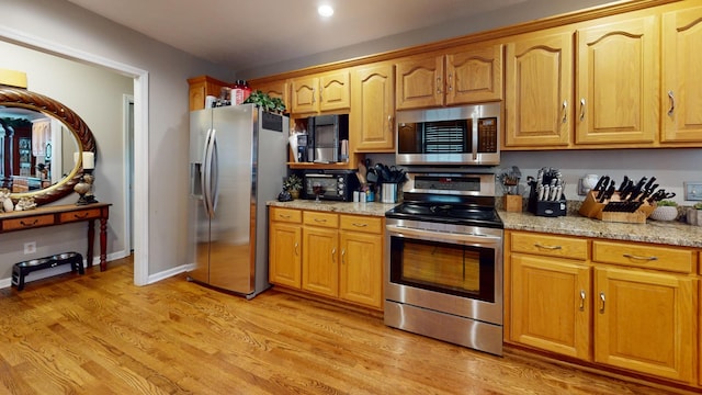 kitchen featuring stainless steel appliances, light stone countertops, and light hardwood / wood-style flooring