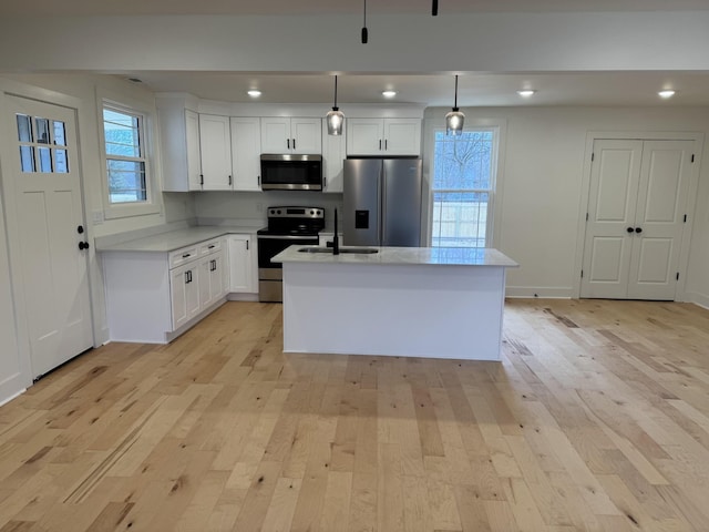 kitchen with white cabinetry, appliances with stainless steel finishes, a kitchen island, and hanging light fixtures