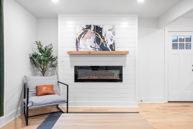 sitting room with a large fireplace and hardwood / wood-style floors