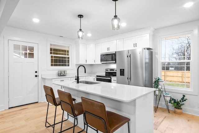 kitchen featuring sink, stainless steel appliances, white cabinets, and a center island with sink