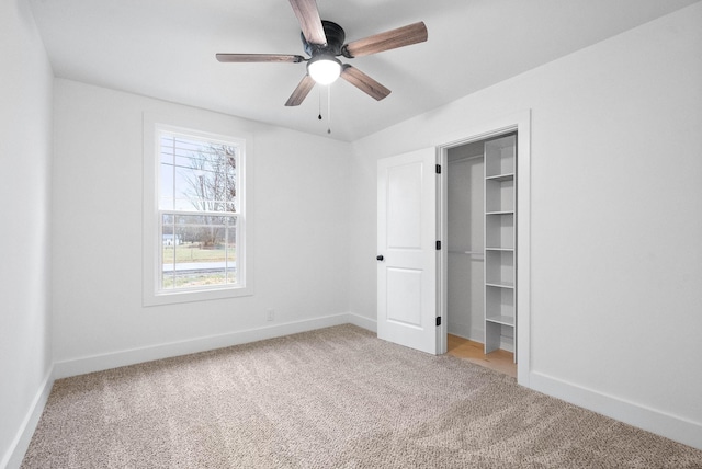 unfurnished bedroom featuring a closet, carpet flooring, ceiling fan, and a spacious closet