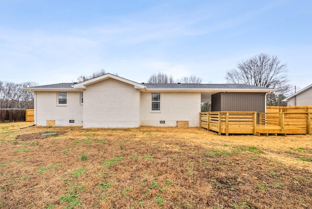 back of property featuring a wooden deck and a lawn