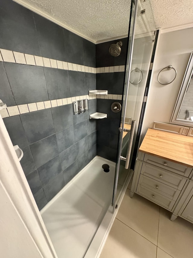 bathroom with a textured ceiling, tile patterned flooring, and a shower stall