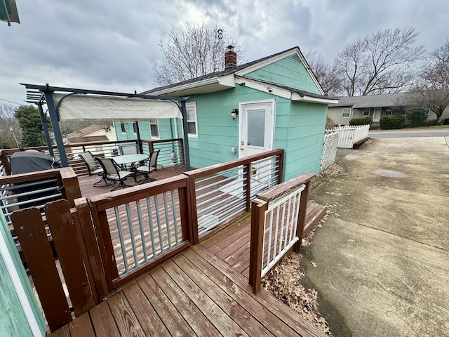 exterior space with outdoor dining space, a chimney, and a wooden deck