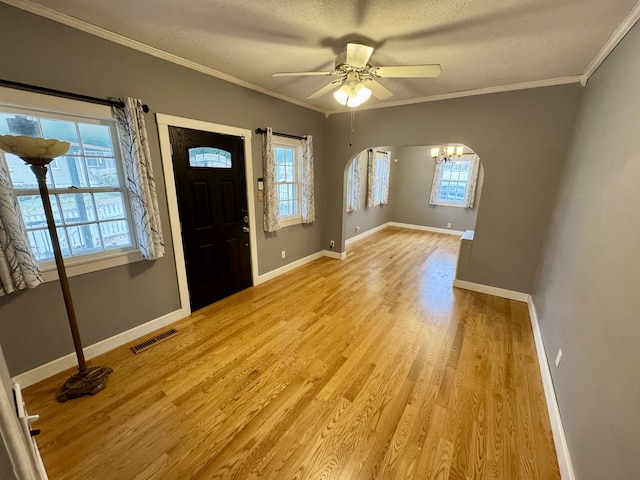 foyer featuring baseboards, visible vents, a textured ceiling, crown molding, and light wood-style floors