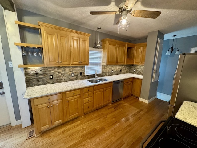 kitchen featuring open shelves, appliances with stainless steel finishes, a sink, and light wood-style floors