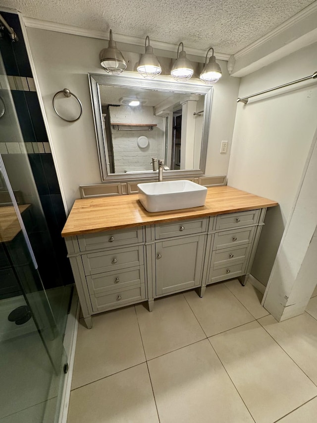 full bath featuring a textured ceiling, vanity, a shower stall, tile patterned floors, and crown molding