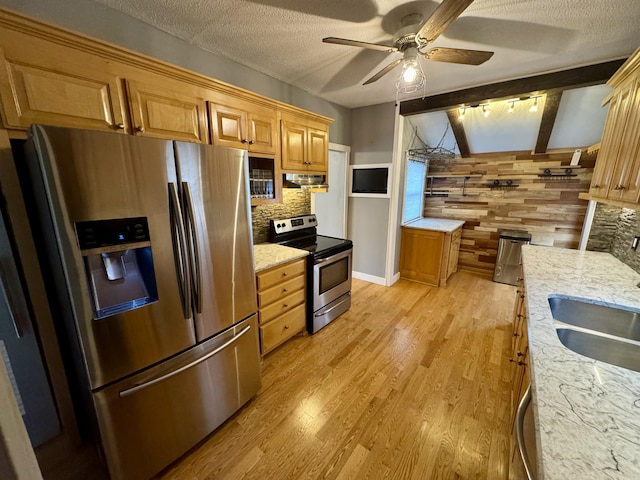 kitchen featuring decorative backsplash, light wood-style flooring, stainless steel appliances, a textured ceiling, and wood walls