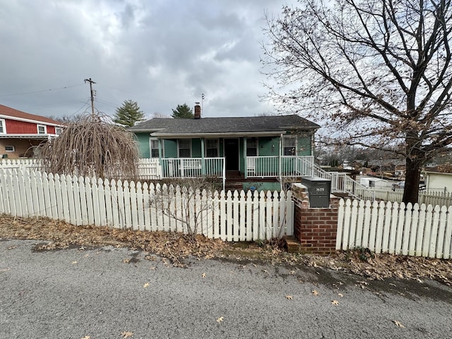 view of front of house featuring a fenced front yard, covered porch, and a chimney