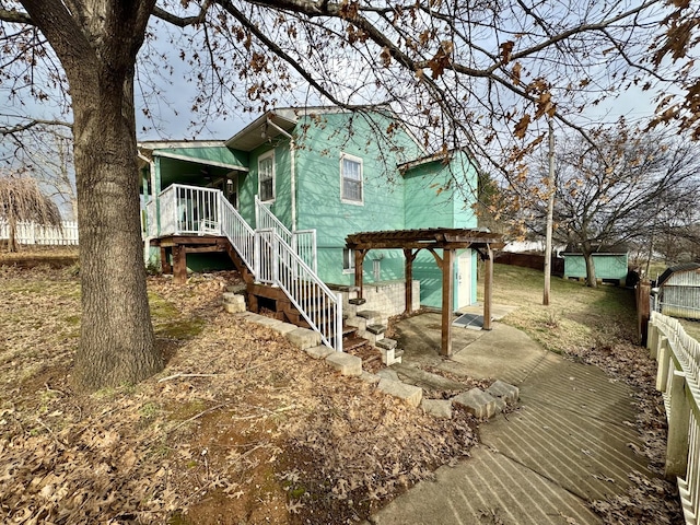 view of home's exterior featuring stairs, fence, a wooden deck, a patio area, and a pergola