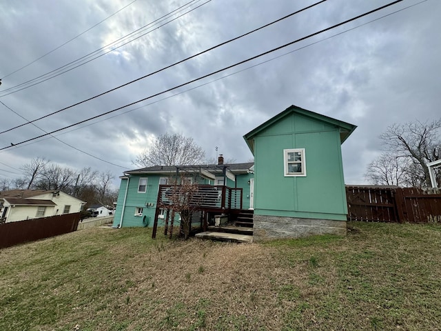 rear view of property with a deck, a lawn, and fence