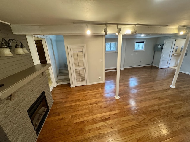 basement featuring stairs, a fireplace, baseboards, and wood finished floors