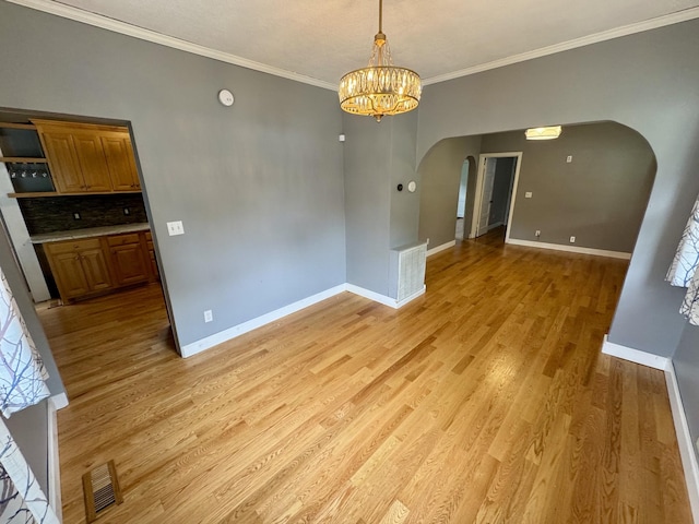 1609 Turner St, Old Hickory, TN 37138 - unfurnished dining area featuring arched walkways, baseboards, light wood-style flooring, crown molding, and a chandelier