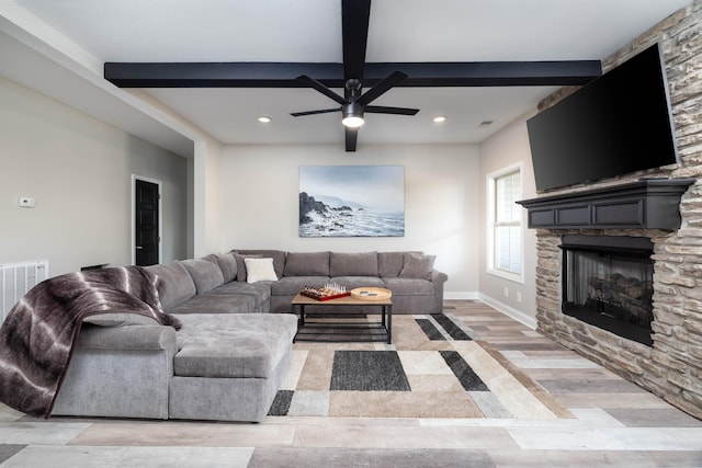 living room with beam ceiling, ceiling fan, a fireplace, and light hardwood / wood-style flooring