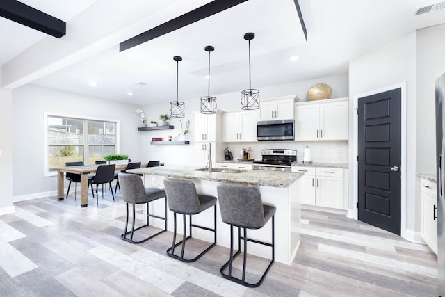 kitchen featuring appliances with stainless steel finishes, sink, an island with sink, and white cabinets