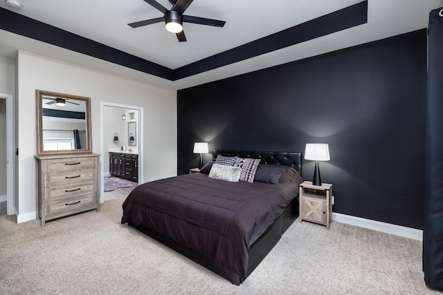 carpeted bedroom featuring a raised ceiling, ceiling fan, and ensuite bathroom