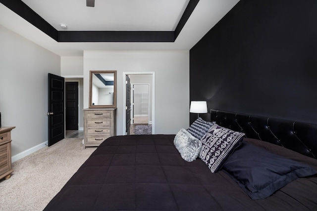 carpeted bedroom featuring ensuite bath, a raised ceiling, and ceiling fan