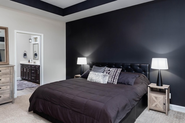 bedroom with light colored carpet, ensuite bathroom, and sink