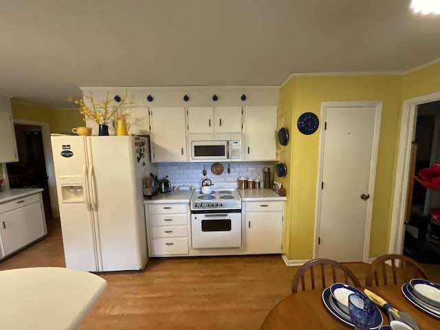 kitchen with white appliances, crown molding, white cabinetry, light hardwood / wood-style floors, and decorative backsplash