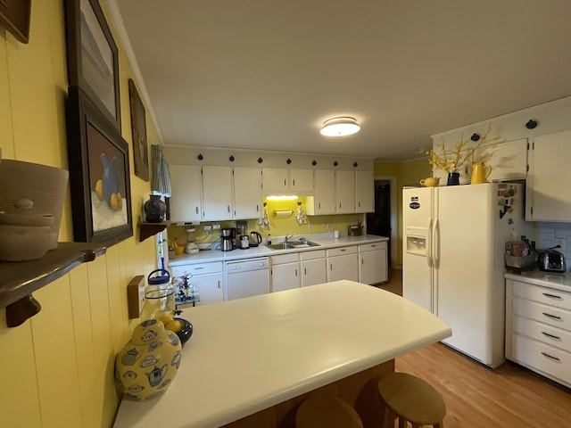 kitchen featuring sink, white appliances, light hardwood / wood-style flooring, white cabinets, and a kitchen bar