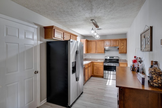 kitchen featuring stainless steel appliances, a textured ceiling, light wood-type flooring, and decorative light fixtures