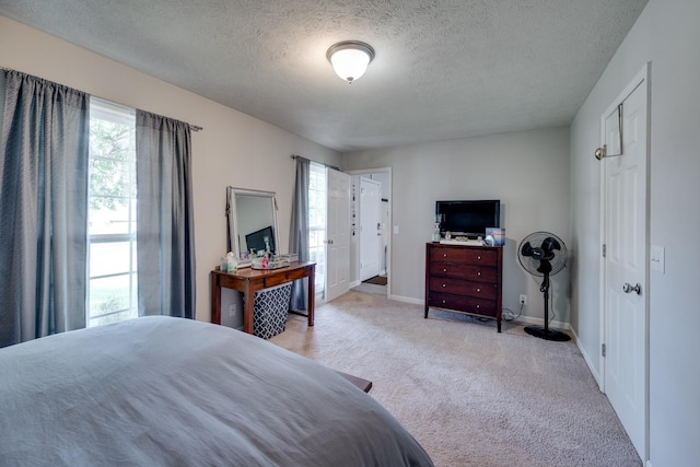 bedroom featuring light carpet, multiple windows, and a textured ceiling