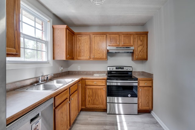 kitchen with stainless steel appliances, sink, and light hardwood / wood-style flooring