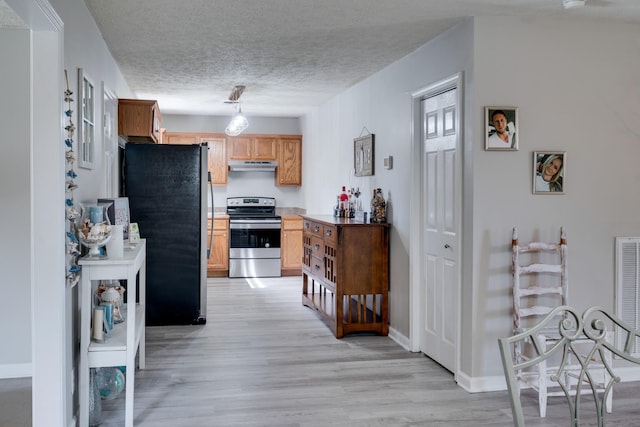 kitchen featuring appliances with stainless steel finishes, decorative light fixtures, light hardwood / wood-style floors, and a textured ceiling