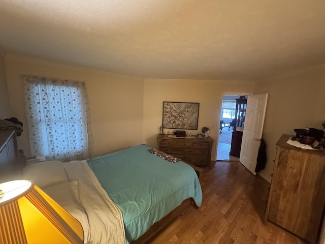 bedroom featuring wood-type flooring, ornamental molding, and a textured ceiling