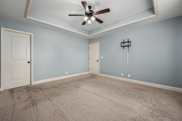 carpeted spare room featuring ceiling fan and a raised ceiling