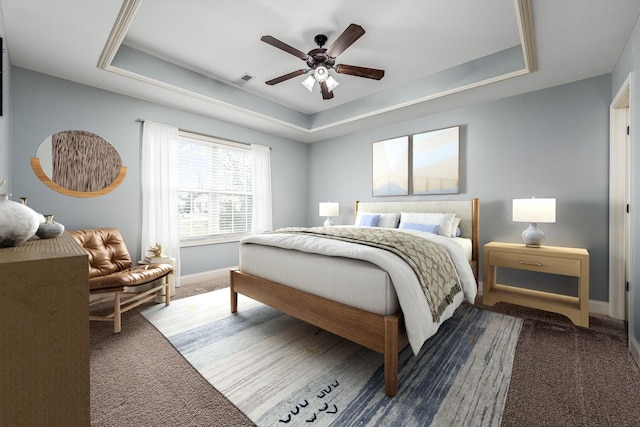 carpeted bedroom featuring ceiling fan and a raised ceiling